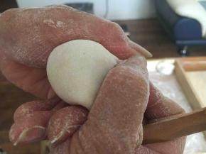 先将饺子皮对折，中间捏紧，然后用双手的拇指和食指将饺子皮的边向中间轻轻挤压。