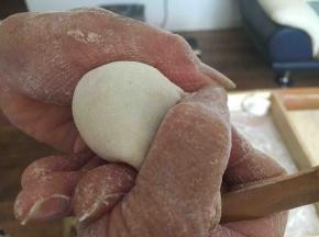 先将饺子皮对折，中间捏紧，然后用双手的拇指和食指将饺子皮的边向中间轻轻挤压。