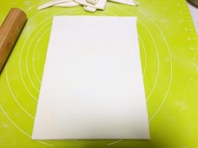 将松弛好的面团擀成0.3厘米厚的薄片，裁掉边缘，让面片成规则的长方形