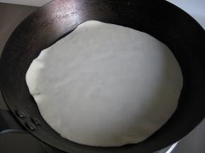 平底锅干锅烧至7成热，务必小火，放入擀好的饼