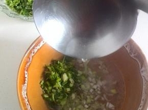 碗里翻入适量的葱花、香菜末，冲入沸腾的羊肉汤