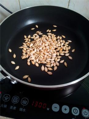 放南瓜籽下去慢慢受热翻炒。等到稍微带微黄的时候搅动一下锅铲。使之受热均匀。