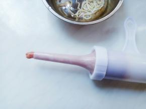 旋转灌肠器的螺旋把手，将肉糜推出入口处露出一小节。