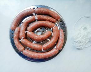 旋转把手，肉糜轻松有节奏的推入肠衣中，一边推肉糜，一边放下肠衣，这个力度掌握好，轻柔点拉动。羊肠衣虽然细薄，但还是有一定的韧性的，熟练了就好。
全部灌好，分段打结。