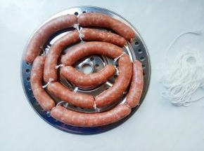 旋转把手，肉糜轻松有节奏的推入肠衣中，一边推肉糜，一边放下肠衣，这个力度掌握好，轻柔点拉动。羊肠衣虽然细薄，但还是有一定的韧性的，熟练了就好。
全部灌好，分段打结。