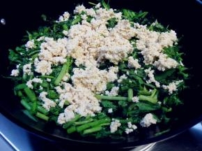 捏碎的豆腐放在茼蒿的上面，勿翻动，盖上盖子用小火焖一会；大约要5分钟时间