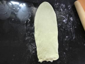 松弛后的面团擀成椭圆形，翻面后压薄长底边。