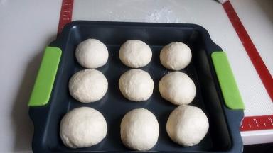 再次按压排气，分割为9份，每个约71克，滚圆，放入烤盘中