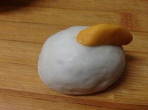 把大的南瓜面团用手整形成扁一点的形状，沾水安装在顶部