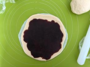 松弛好的面团按扁，擀成6寸大的圆，放在一张8寸的圆形油纸上，然后圆面皮上均匀抹上红豆沙馅