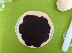 松弛好的面团按扁，擀成6寸大的圆，放在一张8寸的圆形油纸上，然后圆面皮上均匀抹上红豆沙馅