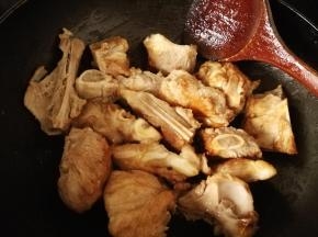 把沥干的棒骨倒入糖浆中，翻炒使之棒骨裹上糖色