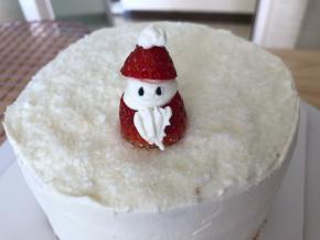 蛋糕顶部撒上椰蓉作为雪花，草莓洗净擦干水分，从1/3处切下，大的一半作为圣诞老人的身体，挤上奶油，盖上小的一半草莓，挤上帽子的白球和圣诞老人的胡须，黑芝麻作为眼睛，放入冰箱冷藏1小时