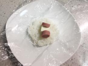 再取30克左右的米饭，包入半块芝士小食，两片火腿片，同样的方法团成小一点的饭团。