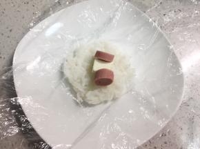 再取30克左右的米饭，包入半块芝士小食，两片火腿片，同样的方法团成小一点的饭团。