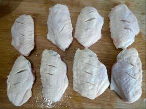 鸡翅中洗净用厨房纸将两面擦干。用刀叉在鸡翅两面扎孔，并在两面划上几刀，方便调料入味。