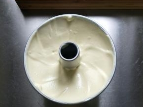 从30cm高处垂直将蛋糕糊倒入模具（这样可以摔碎蛋糕糊中的大气泡），我用的是17cm中空加高款，摁住边缘和烟囱，轻震一下震出内部气泡，用硅胶铲抹平表面…