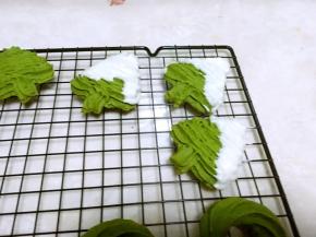 曲奇出炉凉透后，拿起圣诞树的尾部，在白巧克力碗中沾一下，让圣诞树顶部往下的部分裹上一层巧克力，之后放在晾晒网上