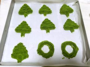 装入裱花袋，我用的8齿裱花嘴，烤盘铺油纸，横着平行挤，一层比一层宽一点，挤上圣诞树的形状，顺便挤了几个圆形，可以做花环，烤箱预热150度烤20分钟