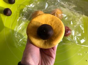 取一个黄色面团，滚圆按扁，包入20g红豆沙（红豆沙提前搓圆）