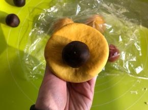取一个黄色面团，滚圆按扁，包入20g红豆沙（红豆沙提前搓圆）