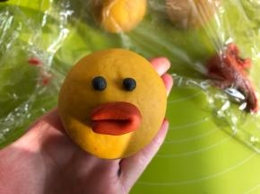 莎莉鸡的眼睛用黑色面团，把橘色面团取一点搓成长条，对折，粘在莎莉鸡的脸上