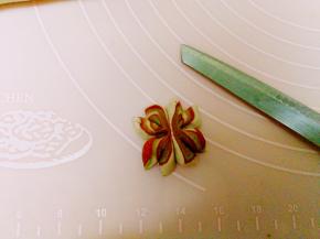 制作炫彩雪花，将四色面团，擀成薄片卷好，搓细长条切小，两个小小面团并排放，用筷子在中间夹一下，再用刀四个花瓣切开，不切断 ，如图