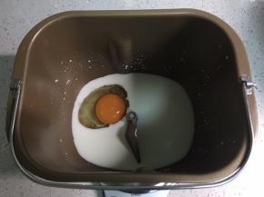 牛奶倒入面包桶，打入一个鸡蛋。