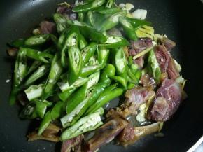 加料酒去除鸭腿的腥味，再放入辣椒翻炒均匀。