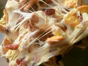 把雪花酥倒入不粘烤盘里，带上手套用手地折叠几下，把棉花糖均匀的粘到每块饼干和坚果上。