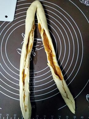 好馅料从一头卷起
滚圆成圆柱形

用刀从中间平均分开
顶端不切

交叉拧起来
直到末端
收口捏紧
