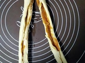 好馅料从一头卷起
滚圆成圆柱形

用刀从中间平均分开
顶端不切

交叉拧起来
直到末端
收口捏紧