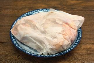 将半只鸡包裹起来，用细小的针头在油纸上戳些小孔，粗盐加热时，会形成一股水蒸气，便于盐粉的香气渗透到鸡肉中，包裹好的鸡肉放在一旁待用