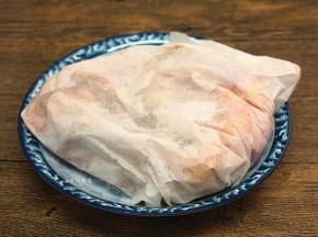 将半只鸡包裹起来，用细小的针头在油纸上戳些小孔，粗盐加热时，会形成一股水蒸气，便于盐粉的香气渗透到鸡肉中，包裹好的鸡肉放在一旁待用