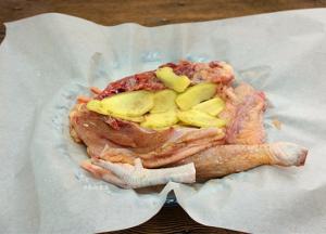 鸡肉两面均匀抹上盐焗鸡粉，摊开油纸，放入鸡肉，将姜片铺在鸡肉上面