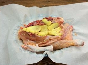 鸡肉两面均匀抹上盐焗鸡粉，摊开油纸，放入鸡肉，将姜片铺在鸡肉上面