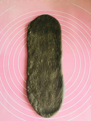 第二次发酵完成，取其中一个面团，轻拍按遍，拍去气泡。从中间往两头擀成牛舌型