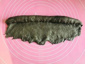 翻面，将它横过来。按扁底部便于收口。从上往下卷，边卷边按压。