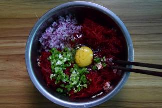 肉末中加入甜菜根丝、洋葱、葱末和燕麦片，加适量盐，再打入一个鸡蛋拌匀