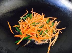 放入胡萝卜丝和蒜苔，煸炒几下，使胡萝卜断生。