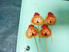 黑芝麻做眼睛，用棍子把草莓头一起穿起来