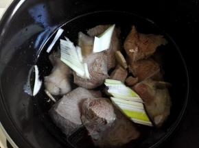 高压锅里加入适量清水，将牛肉放进去，再放适量的葱段和姜片，