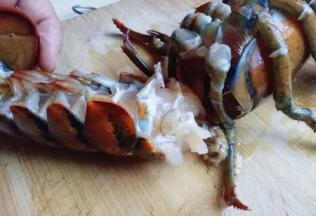 用小尖刀从大龙虾的身体和头部处插入刀。(也就是虾腮的地方。这样龙虾头和尾部就分开了。