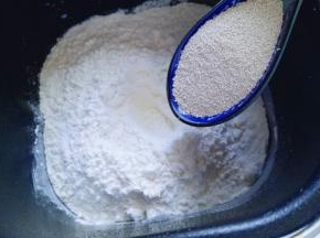 加入高筋面粉，奶粉，再面粉的顶端挖个小洞，(注意不要挖到液体) 然后把酵母粉倒入挖好的小洞里。再将莲藕盖起来。