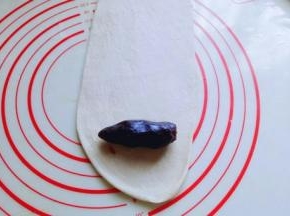 准备好豆沙馅，我是买的豆沙馅，使用自己做的也可以。取一块松弛好的面团，用擀面杖擀成长舌状，再把豆沙馅放上去。(也可以把豆沙馅压扁，和面团一起擀成长舌状，根据个人喜欢来。)