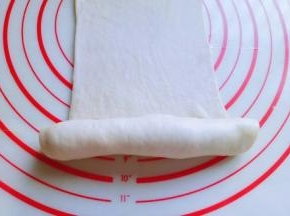 再长舌状面皮的另一端从下往上卷起来，卷到一半时停下来，如图。