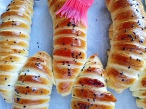 戴上隔热手套取出烤盘，立即刷上一层玉米油，这样会更好的锁住面包的水份。