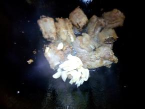 大火煎至排骨表面金黄，放蒜炒香。