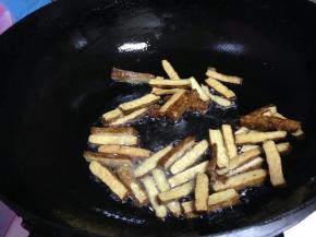 原锅再加入少量的油，倒入香干煎至表面起痂捞出备用