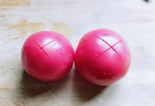 首先将番茄洗干净，再顶端用刀划出十字刀。